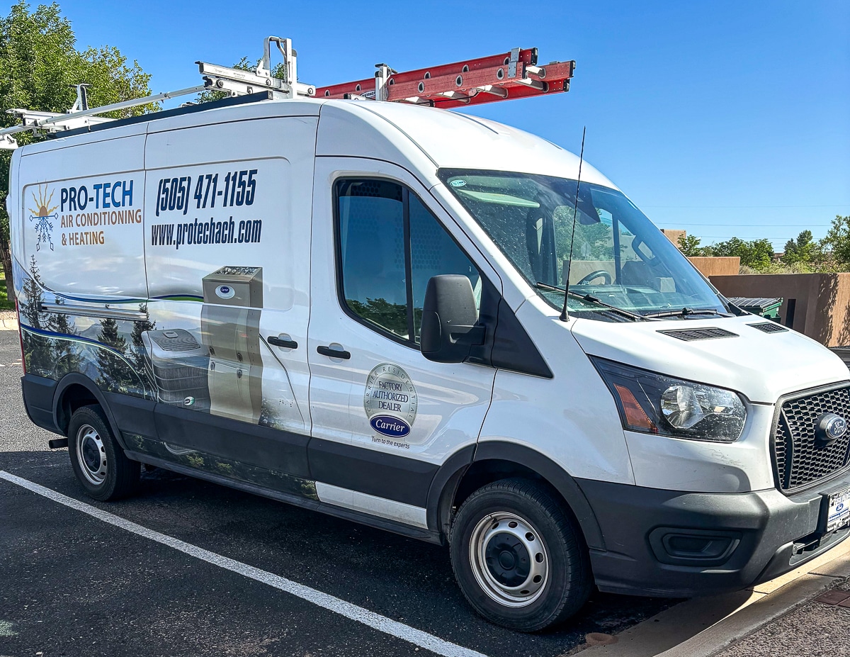 White Pro-Tech Air Conditioning & Heating van with a roof ladder rack parked in a lot; side logo, phone (505) 471-1155 and website text visible on the panel.